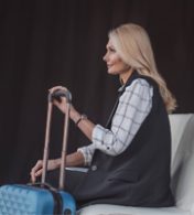 mulher loira com uma mala esperando para embarcar em uma viagem