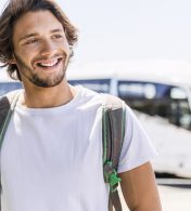 homem sorrindo com um ônibus ao fundo
