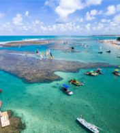 praia de águas límpidas e alguns barcos no nordeste