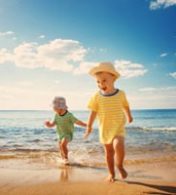 dois bebês sorrindo e caminhando na praia